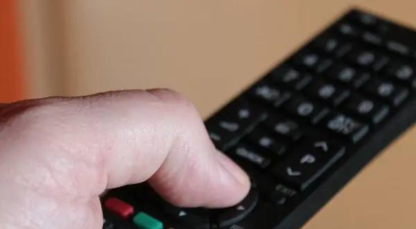 Dłoń trzymająca pilot do telewizora Samsung, naciskająca przyciski.
