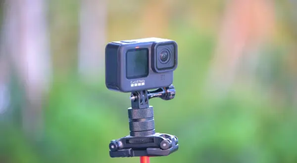 GoPro Hero 10 na statywie z czerwonym mocowaniem, na tle zieleni.